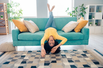 Full length photo of overjoyed pretty cheerful person sit couch upside down free time modern flat...
