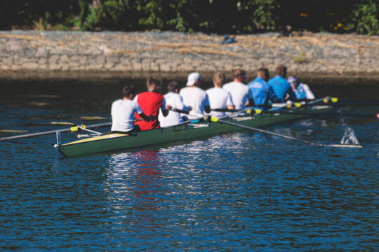 Group of rowing team athletes sculling during competition, kayak boats race in a rowing canal, regatta in a summer sunny day, canoeing water sports team training in a river