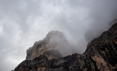 Cloudy fogy sky mountain peaks covered in mist in the morning. Dolomite rocky mountains Italy