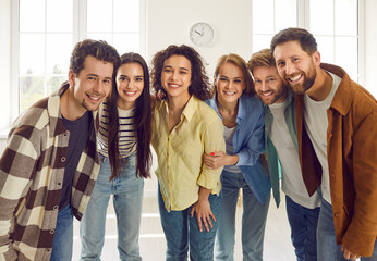 Group of happy smiling funny friends students or colleagues in casual clothes standing together and...