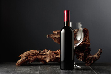 Red wine and old weathered snag on a black stone table.