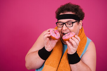 Funny fat man enjoys life and eats donuts. Fitness in the early morning.