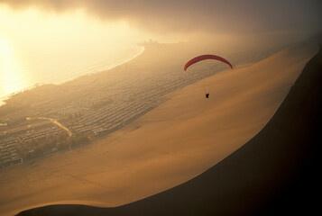 Paraglider over El Dragon, a large sand dune near Iquique, Chile at the edge of the Atacama Desert;...