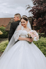 The bride and groom stand back to back. a couple of newlyweds, bride and groom, at a wedding in nature, green forest, kisses, photo portrait. Wedding couple