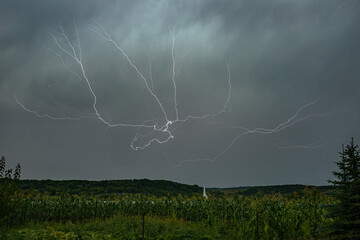 Whimsical branched lightning high in the sky over the hilly landscape of Transylvania, Romania