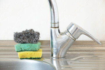 Dirty kitchen sponges and a metal ruff lie on the kitchen sink in the kitchen