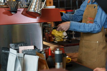 Close-up hand Asian woman shop owner, who is working as barista in own cafe, is bringing machine that contains pre-ground coffee assemble coffee maker, making menus according customer orders.
