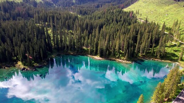 Idyllic nature scenery- trasparent mountain lake Carezza surrounded by Dolomites rocks- one of the most beautiful lakes of Alps. South Tyrol region. Italy, aerial drone video