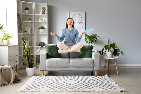 Flying young woman with book over sofa at home