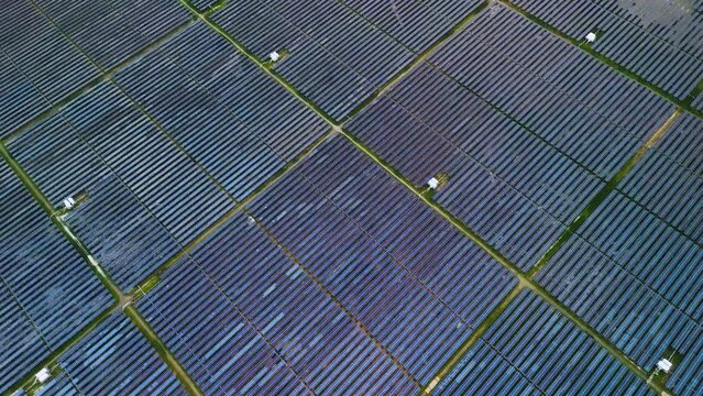 Aerial view of large sustainable electrical power plant with many rows of solar photovoltaic panels in countryside with cloudy sky in Tay Ninh, Vietnam