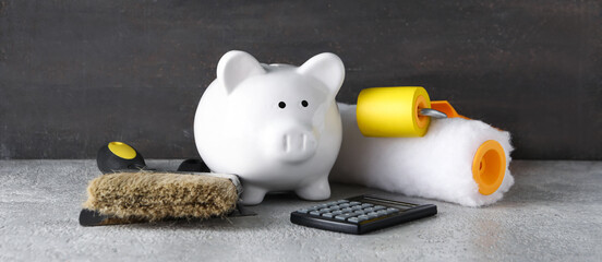 Piggy bank, calculator and painting tools on black grunge background