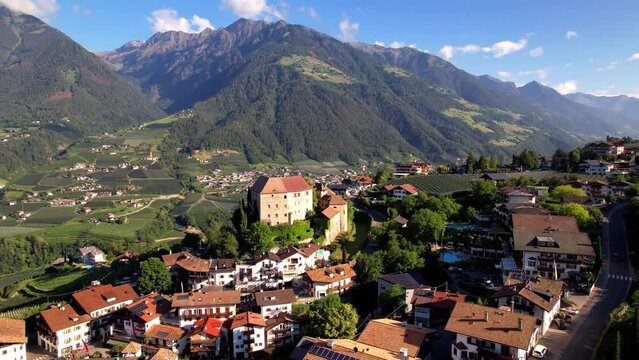 Italy Schenna aerial drone fly-out reveal of medieval castle village and Alps mountains in South Tyrol near Merano Bolzano. Scenic vineyards landscape and traditional architecture Trentino Alto Adige