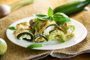 cooked zucchini rolls with cheese filling inside, in a plate