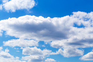 Naklejka na ściany i meble Fluffy white clouds in clear blue sky. Beautiful natural background for your design