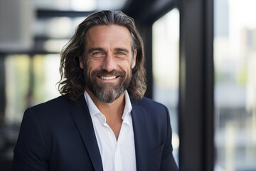 Fototapeta premium Middle aged caucasian businessman with long hair and a beard in the office smiling