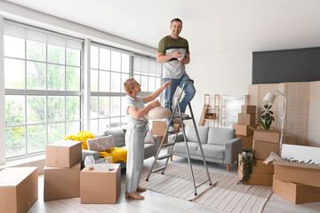 Mature couple with ceiling lamp in room on moving day