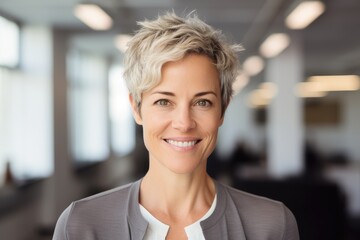 Obraz premium Middle aged businesswoman with short hair smiling and looking at camera in office