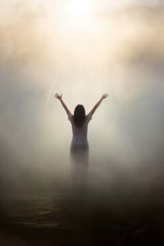 healing concept. miracles. woman praying with her arms raised.