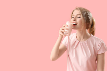 Young woman drinking tasty yoghurt on pink background