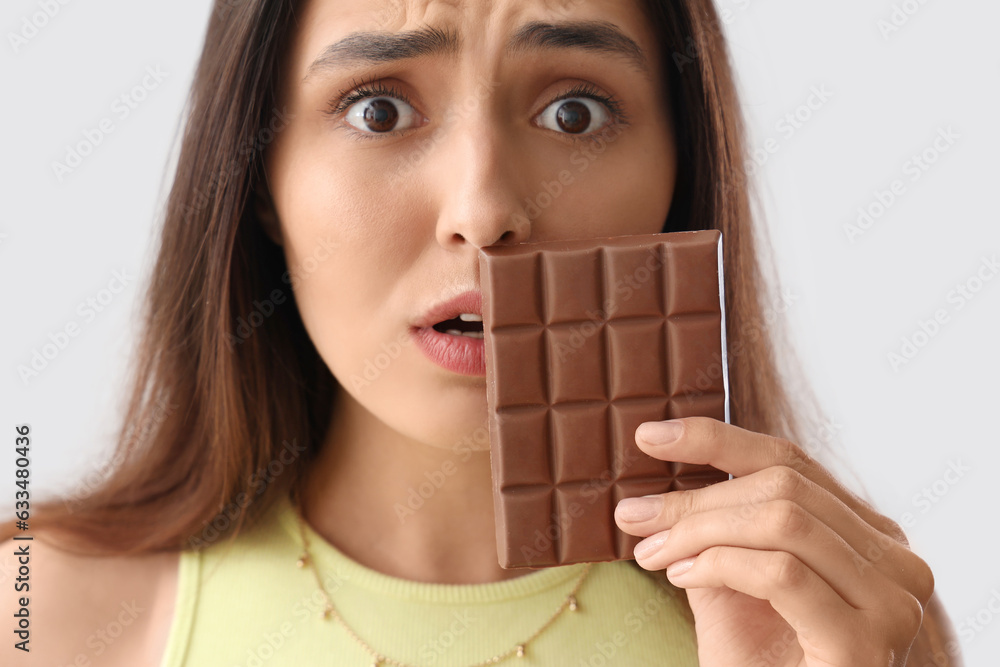 Canvas Prints Worried young woman with tasty chocolate on light background,closeup