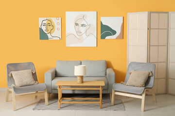 Interior of stylish living room with grey sofa, armchairs and paintings