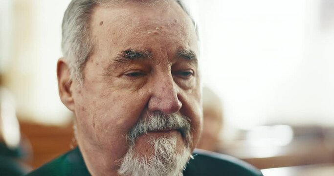 Sad, senior man and face closeup at a funeral in church for religious service and mourning. Grief, male person and burial with death, ceremony and grieving of chapel event of family member or friend