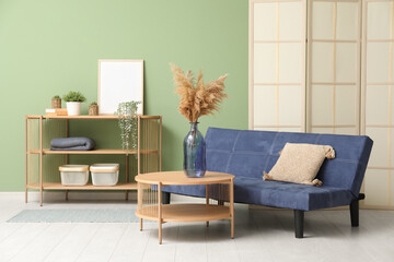 Wooden coffee table with shelving unit and couch near green wall