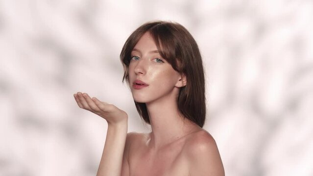 Attractive brunette female model with long hair and blue eyes blowing off the feathers. Slow motion