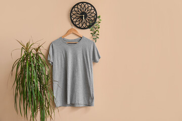 Stylish grey t-shirt hanging on beige background
