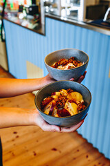 hands holding of waiter holding two bowl with yogurt and fruits. healthy food