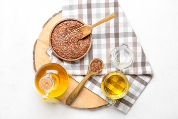 Wooden board with flax oil and seeds on light background