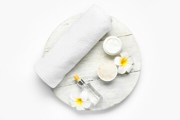 Wooden board with cosmetic products, clean towel and flowers on white background