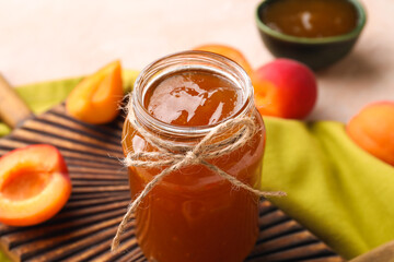 Jar with sweet apricot jam on pink background