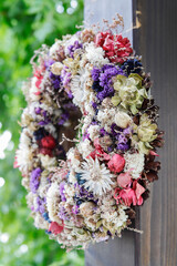 A beautiful wreath made of dry plants is hanging on a porch.