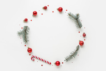 Frame made of Christmas tree branches with balls and candy cane on white background