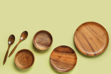 Wooden plates and spoons on green background