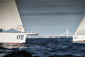 Bowsprit of sailing yachts are in sailing regatta at sunset, the clear sky, hot racing, bridge