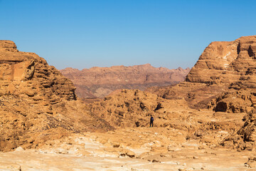 Fototapeta na wymiar Sinai desert. Yellow and orange sandstone textured carved mountain, bright blue sky. Egyptian desert landscape. Sinai peninsula, Egypt
