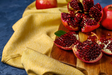 Wooden board with fresh pomegranates on blue background