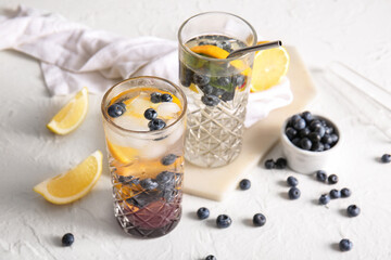 Glasses of fresh blueberry lemonade and bowl with berries on white background