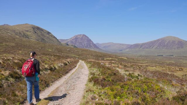 Rear view of hiker walking past on West Highland Way trail on a sunny spring afternoon, Scotland, UK