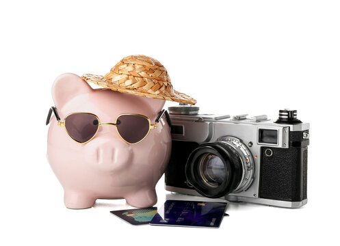 Piggy bank with beach accessories, camera and credit cards on white background. Concept of savings for travel