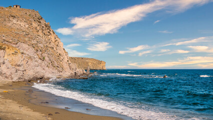 clouds cluster  in the sky on a deserted beach with magnificent cliffs and sea waves