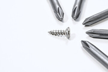 Steel industrial screw surrounded by screwdrivers tips.