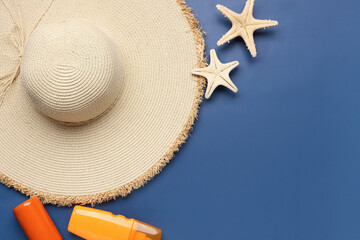 Composition with stylish straw hat, bottles of sunscreen cream and starfishes on color background