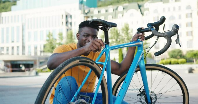 Positive African American unscrews bolt from bicycle seat