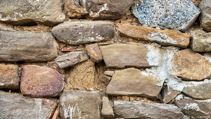 old stone wall background in various colors. The wall of the old historical stone house built with stones one by one