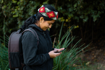 Joven hermosa sosteniendo un tel&eacute;fono inteligente en el campo conjunto con flores al fondo