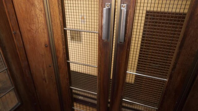 Going up in an old-fashioned wooden elevator with glass windows.