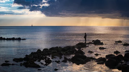 Fotobehang Un pêcheur sur les rochers au bord de l'océan indien, devant un ciel menaçant © Pascal